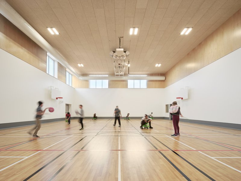 Gymnasium with timber floor and plywood ceiling where children play basketball in motion blur