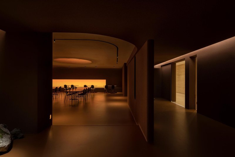 Curved corridor leading to a seating area with backlit amber wall at the end