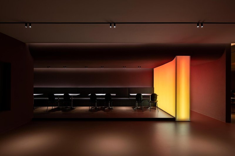 Long view through a series of recessed dining zones with backlit gradient wall panels