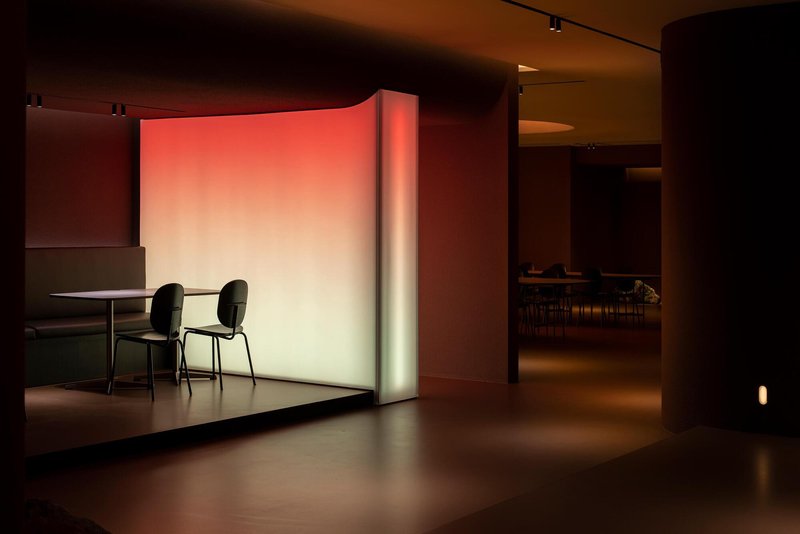 Seating nook with two chairs and table against a gradient illuminated wall in warm tones