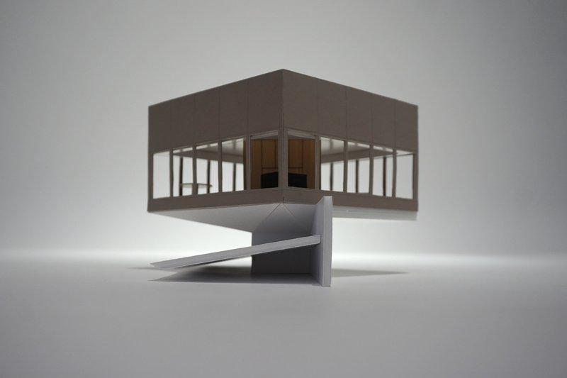 Physical model of an elevated pavilion on a concrete pedestal with a folded access ramp