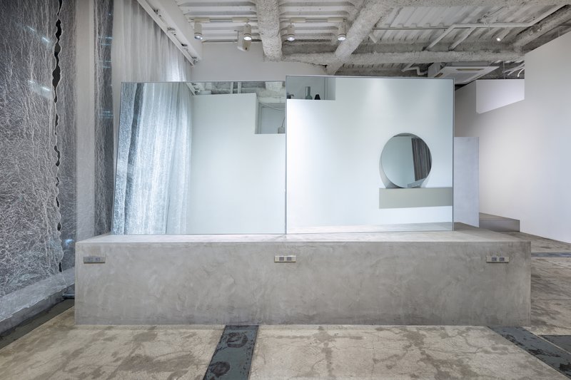 Long concrete counter with embedded outlets facing white partitions and exposed structural beams overhead