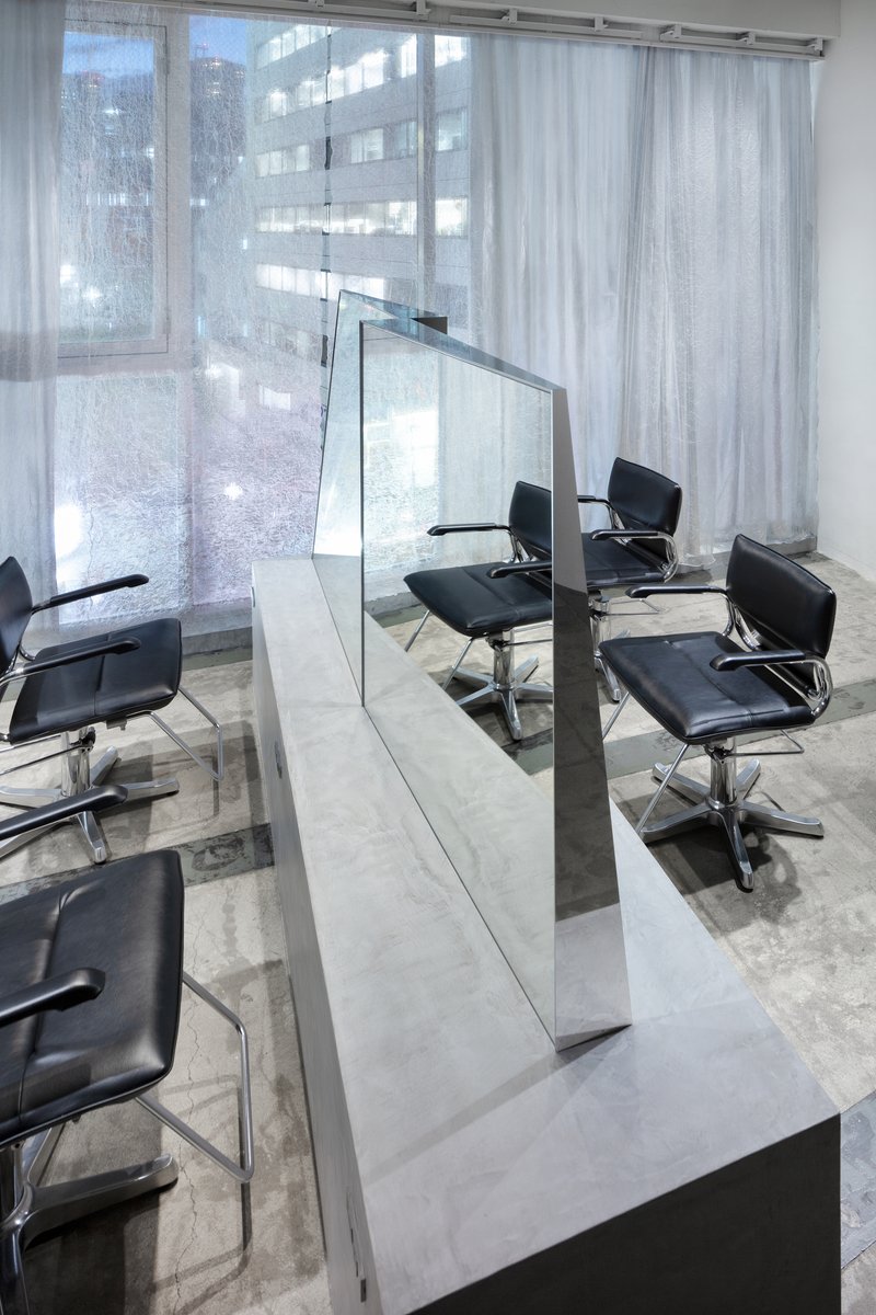 Interior salon with white styling stations flanked by glass dividers and sheer curtains filtering daylight