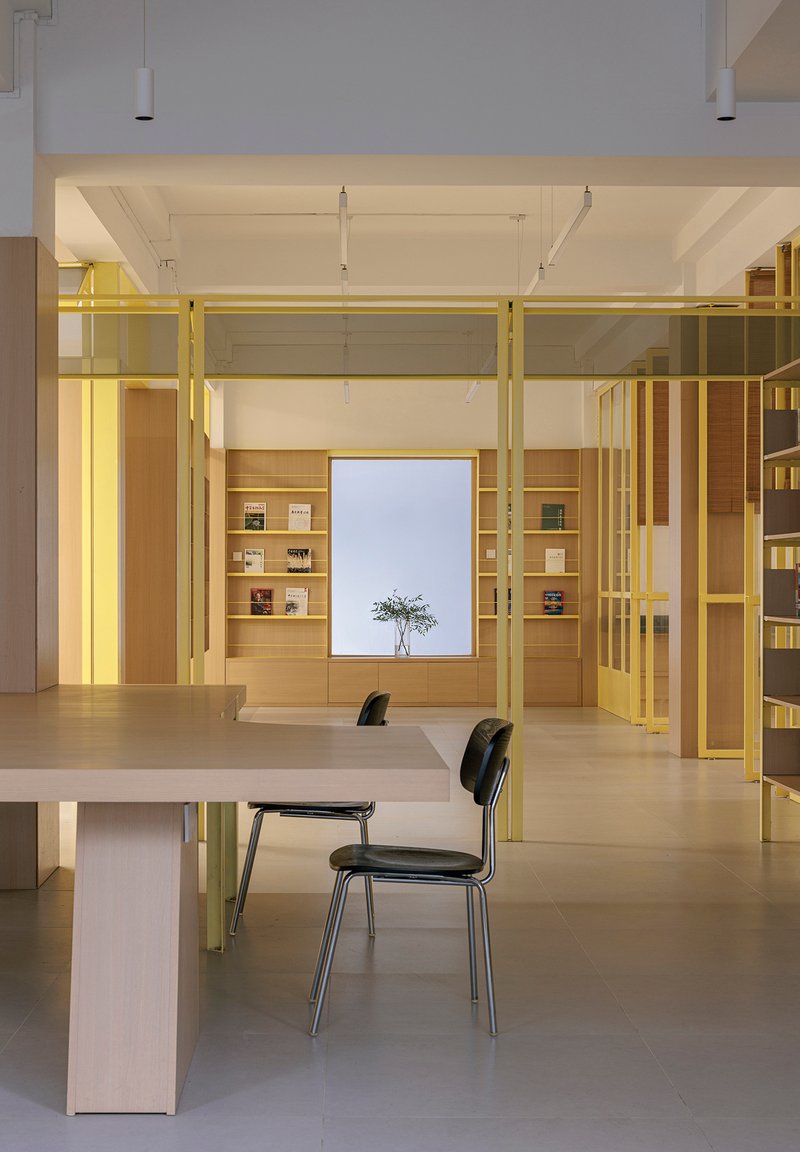 Reading area with yellow steel structural frame and central window flanked by oak shelving