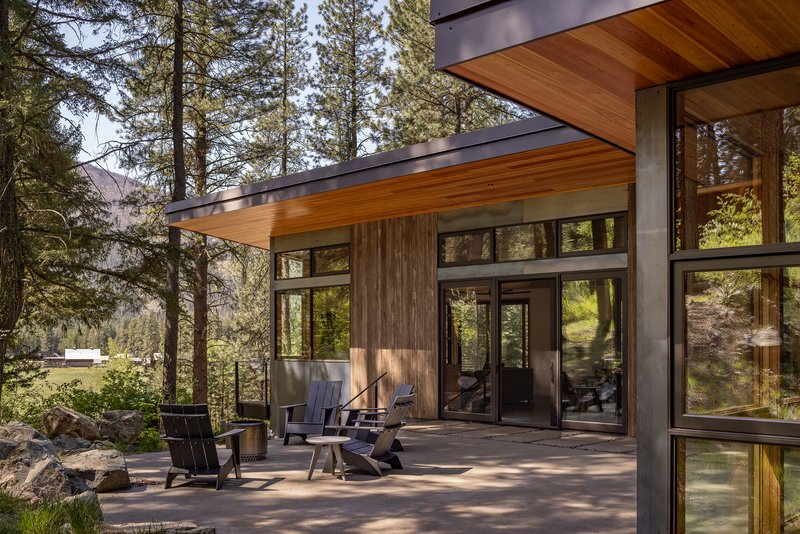 Concrete terrace with timber-framed glazing and cedar soffit overlooking the forest with outdoor seating