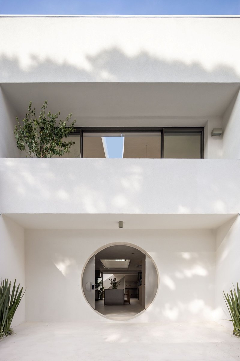 White stucco facade with circular entry portal framing the kitchen island under cloudy skies