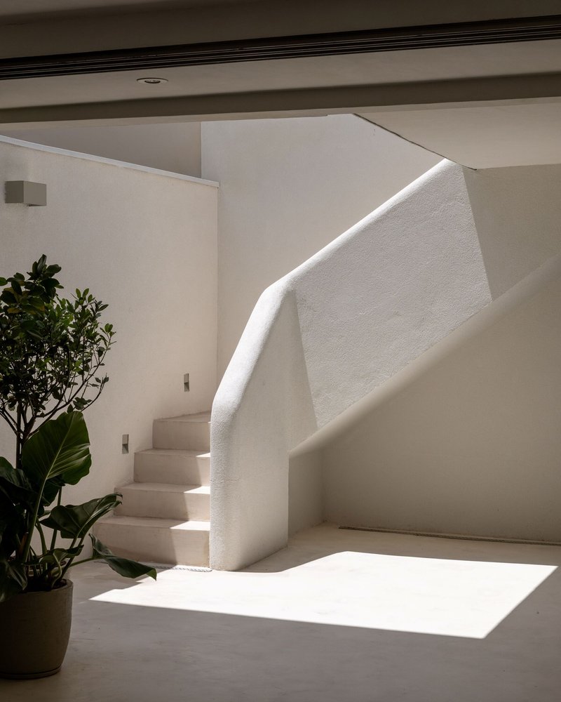 White plastered staircase with integral handrail illuminated by natural light from above