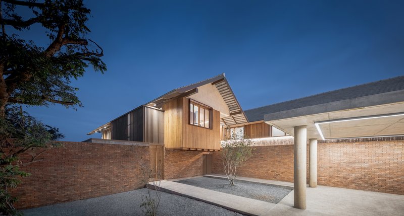 Covered carport entry with white columns and brick walls framing a courtyard tree at twilight