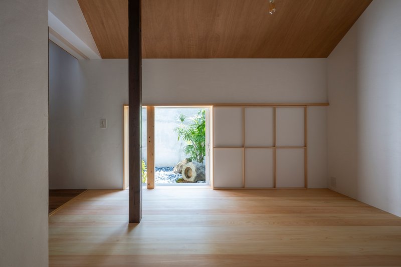 Light-filled room with timber floors, shoji screen and framed opening to a small courtyard garden