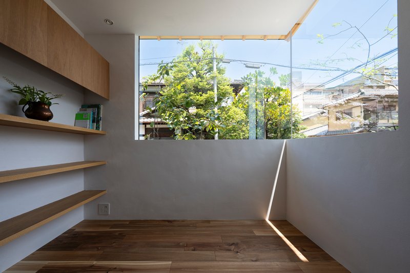 Corner study nook with timber shelving and high clerestory window overlooking neighboring rooftops