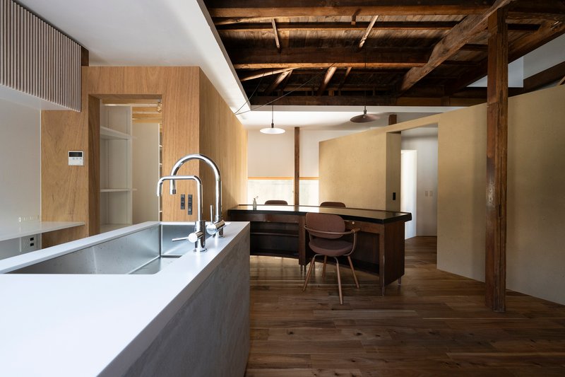 Kitchen island with white countertop and dining area beneath exposed timber beams and joists