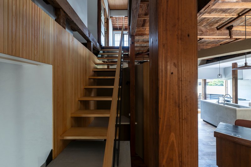 Timber staircase with open risers ascending between vertical wood columns and slatted wall panels