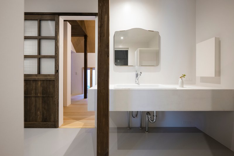Bathroom vanity with floating white sink and curved mirror beside a sliding timber and glass door