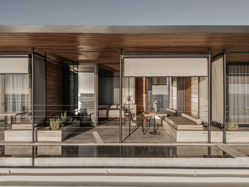 Glass-enclosed terrace with sliding panels and timber ceiling opening onto a reflecting pool