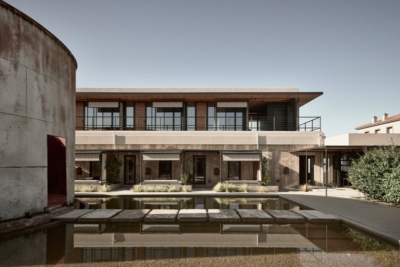 Courtyard pool with stepping stones reflecting the concrete cylinder and two-story residential wings