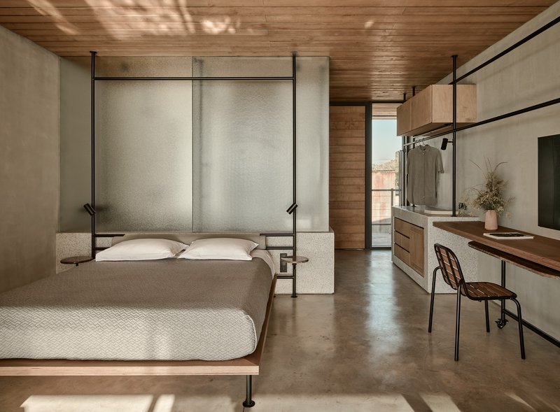 Bedroom with translucent panel headboard and concrete partition beneath slatted timber ceiling