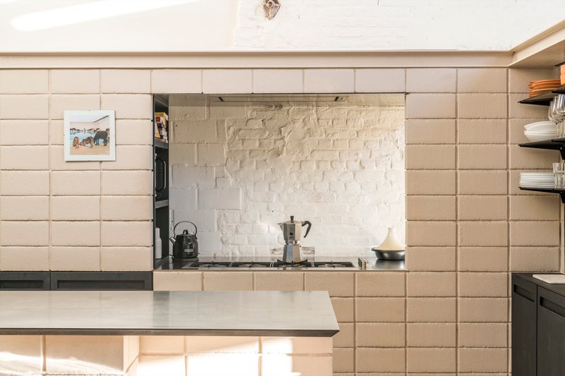 Kitchen nook with horizontal tile cladding, painted brick backsplash and open shelving under strip lighting