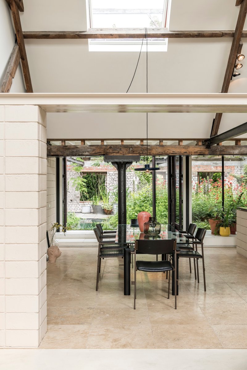 Dining area with exposed timber beams and steel structure overlooking a garden through floor-to-ceiling glazing