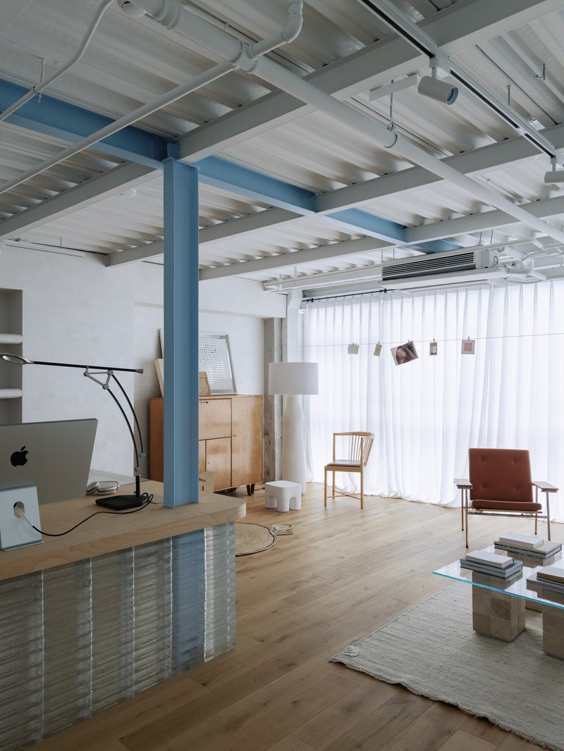 Living area with blue steel column and white ribbed ceiling structure above timber flooring