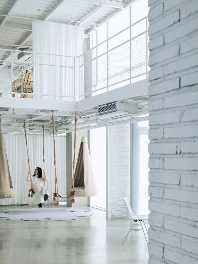 Interior with rope swings suspended from ceiling beside painted brick wall and glazed partition