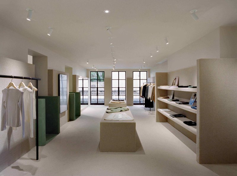 Retail space with cork-textured shelving, green partitions and black-framed windows opening to courtyard