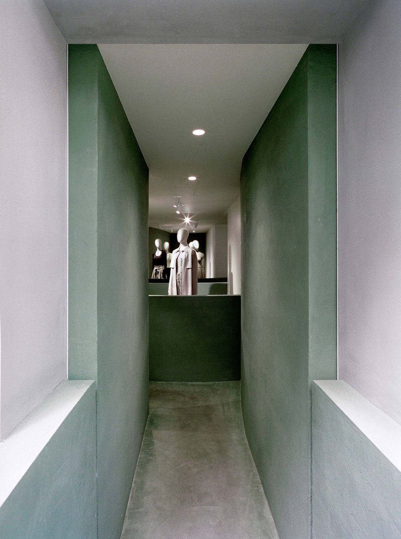 Narrow corridor with green plaster walls leading to a display counter at the end