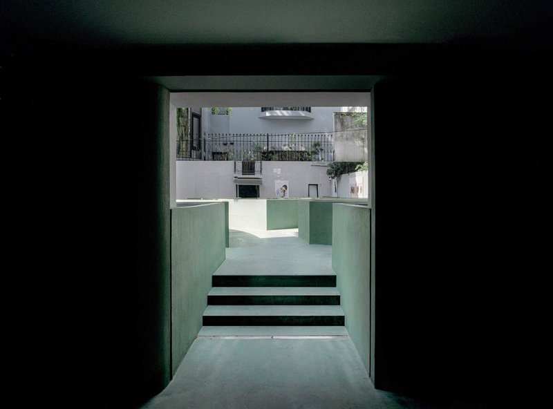 View through green plaster doorway to steps ascending toward a courtyard beyond