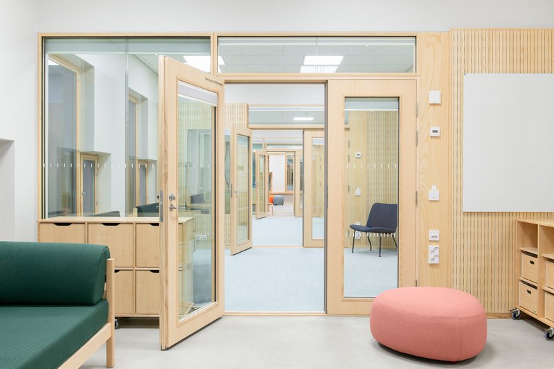 Interior corridor with timber-framed glass doors opening between rooms with light wood joinery