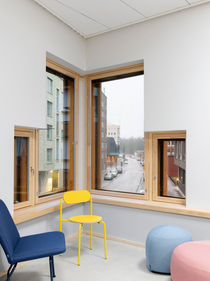 Corner window seat with timber frames looking onto a winter street with parked cars