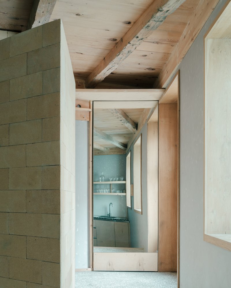 Interior passage with timber doorframe and glimpse of kitchen beyond plaster walls
