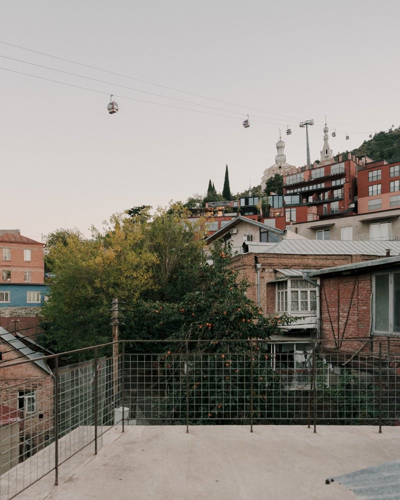 Rooftop terrace with glass railing looking toward hillside neighborhood and cable car lines