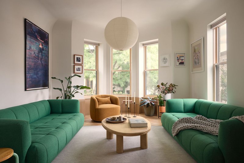 Living room with green channeled sofas around a circular timber coffee table and spherical pendant in daylight
