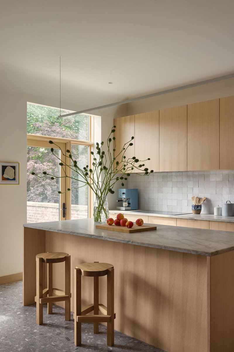 Kitchen island with stone countertop and timber cabinetry below clerestory window with garden view