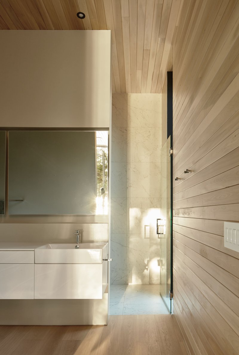 Bathroom vanity beside a narrow glazed slot framing sunlight and trees beyond
