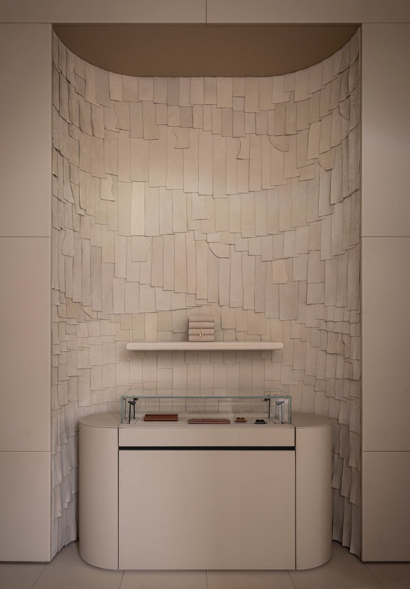 Curved alcove with irregular beige tile mosaic wall above a vanity with glass countertop