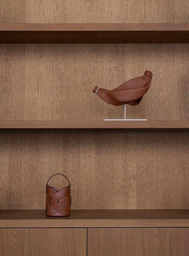 Built-in shelving with oak veneer displaying a sculptural bird form and leather vessels