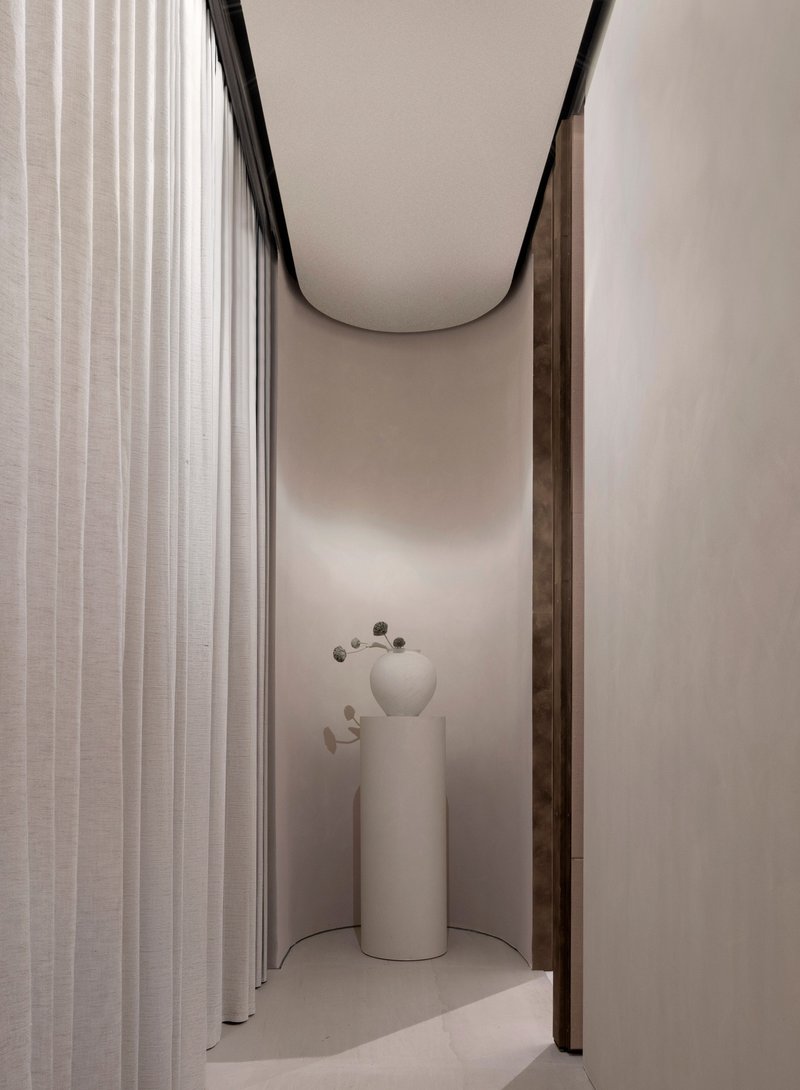 Narrow alcove with curved ceiling soffit and cylindrical pedestals holding ceramic vases
