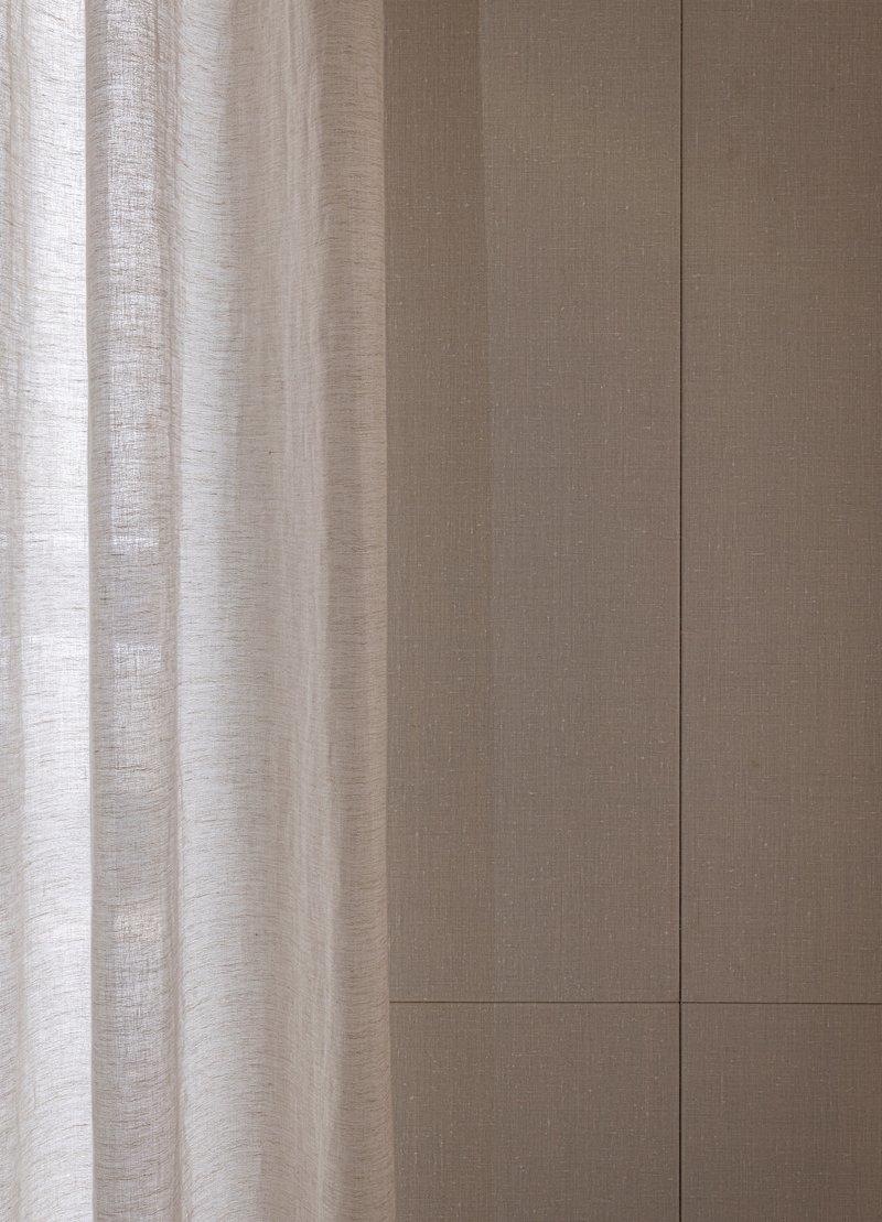 Linen curtain beside grooved oak wall panels with horizontal joint detail in natural light