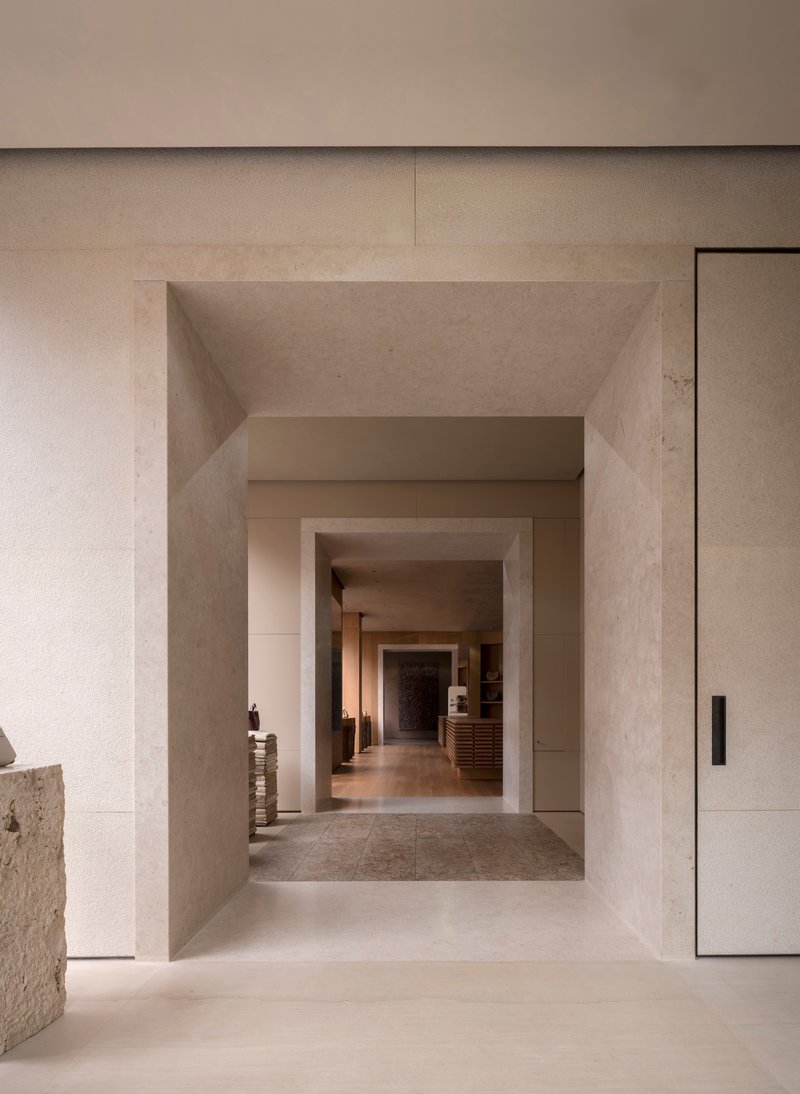 Sequence of thick stone portal frames receding through a gallery corridor with polished floors