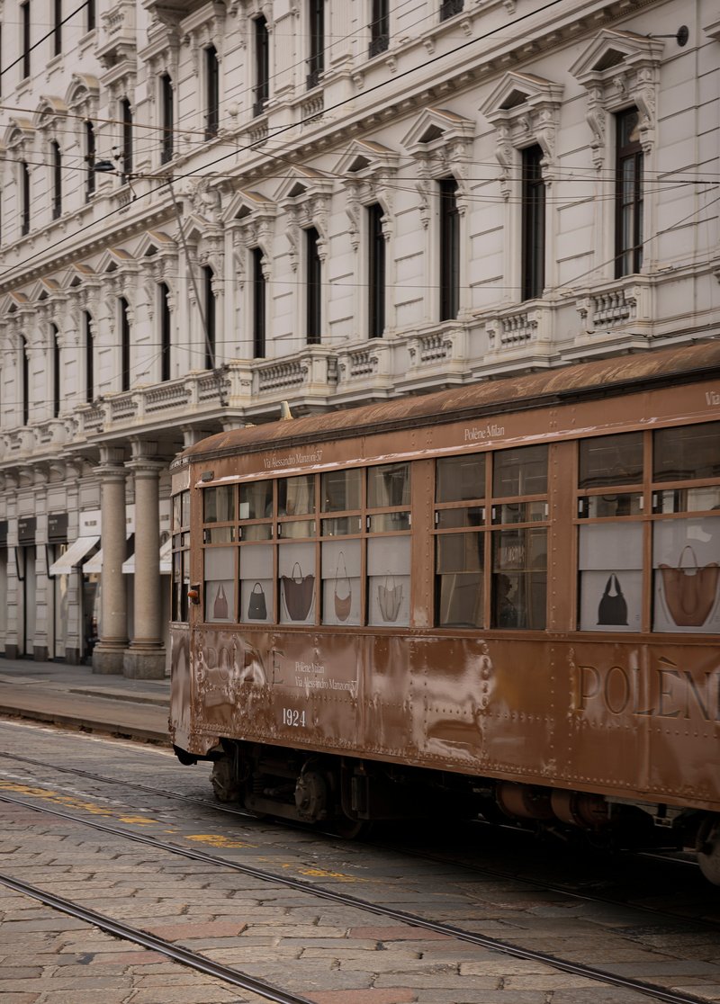 Historic tramcar passing a cream stuccoed facade with tall windows and ornamental balustrading
