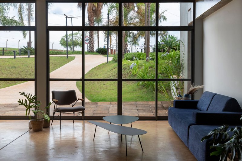 Interior lounge with floor-to-ceiling windows overlooking the lawn and palm trees outside