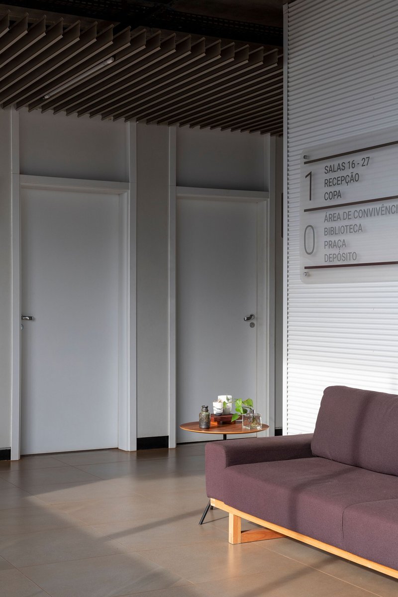 Interior corner with flush white doors beneath a wood slat ceiling and wayfinding signage