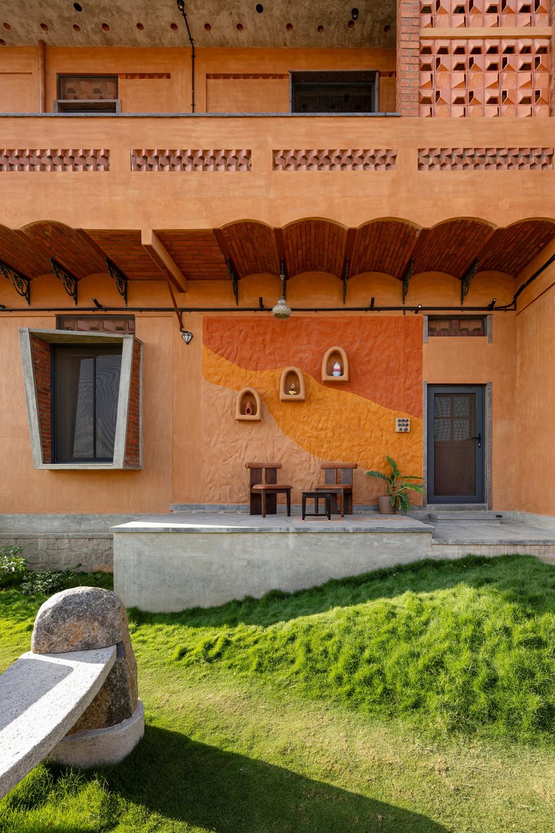 Covered terrace with exposed brick vaulted ceiling, niche wall ornaments, and lawn below