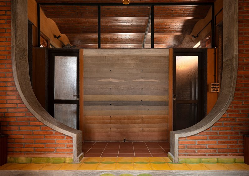 Entrance with curved concrete frame and layered timber door flanked by frosted glass panels