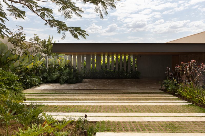 Concrete drive with alternating grass strips leading to a covered carport with vertical metal screens