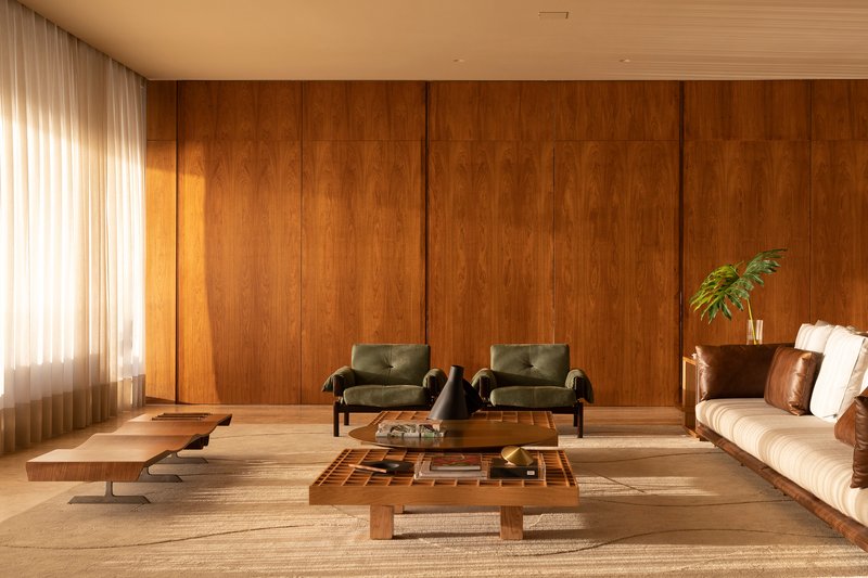 Living room with vertical timber wall panels and sheer curtains filtering daylight beside low seating