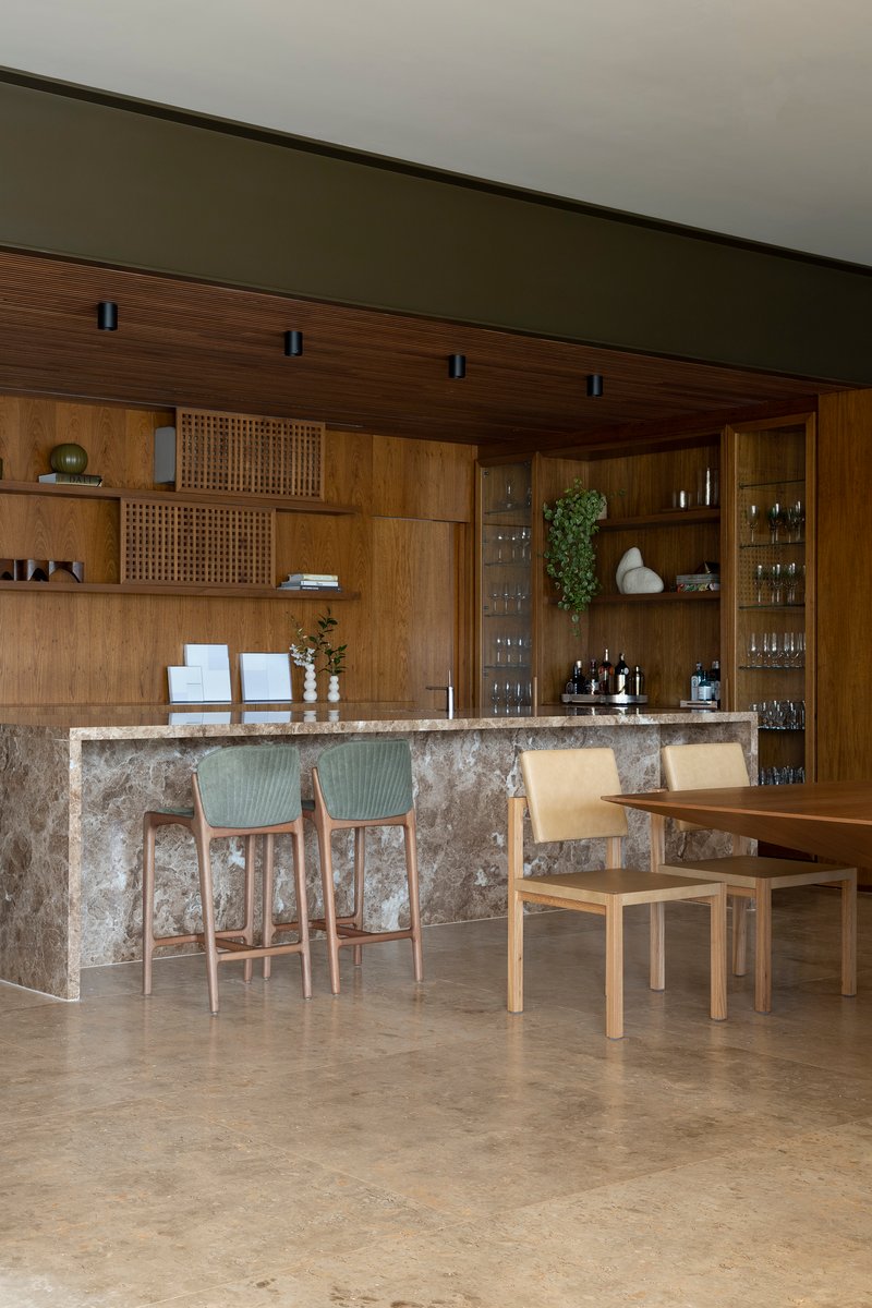 Kitchen bar with textured stone counter, timber cabinetry, and pendant lighting above dining seating