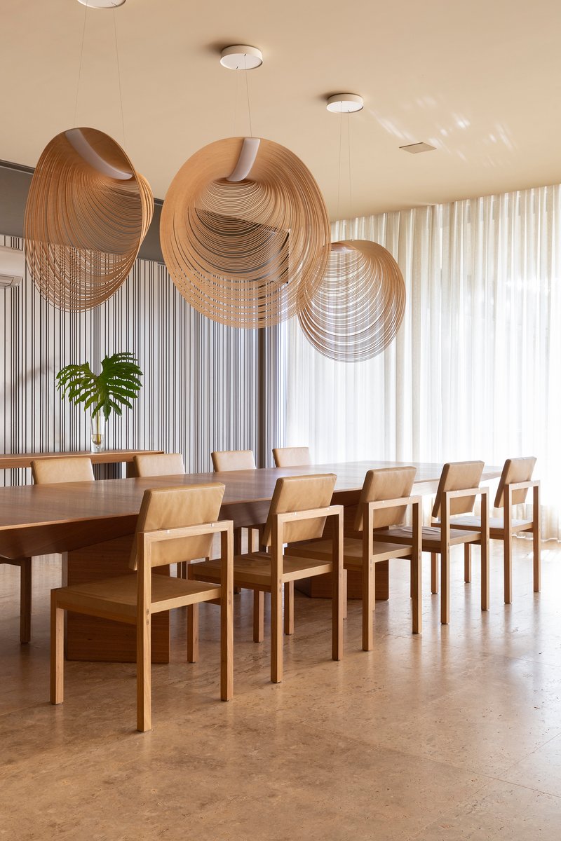 Dining room with layered circular timber pendant lights suspended over a long table and chairs
