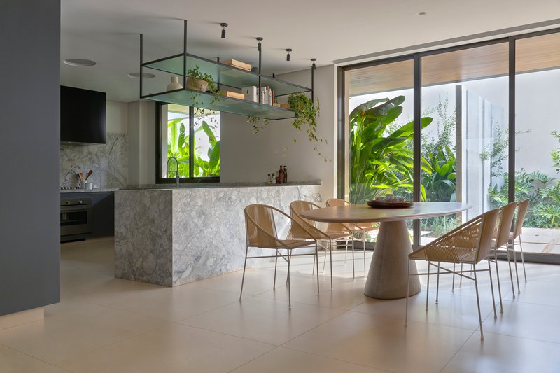 Open kitchen and dining area with marble island and glazed walls framing tropical plantings outside
