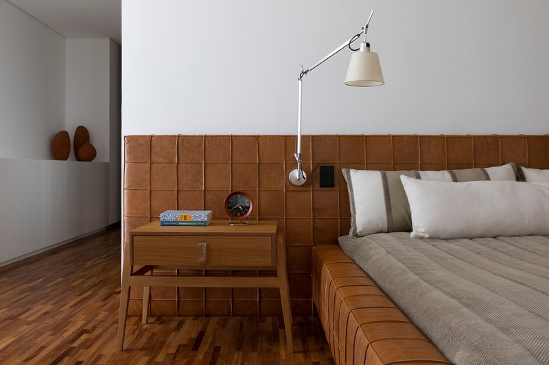 Close-up of the stitched leather headboard with swing-arm wall lamp and timber nightstand